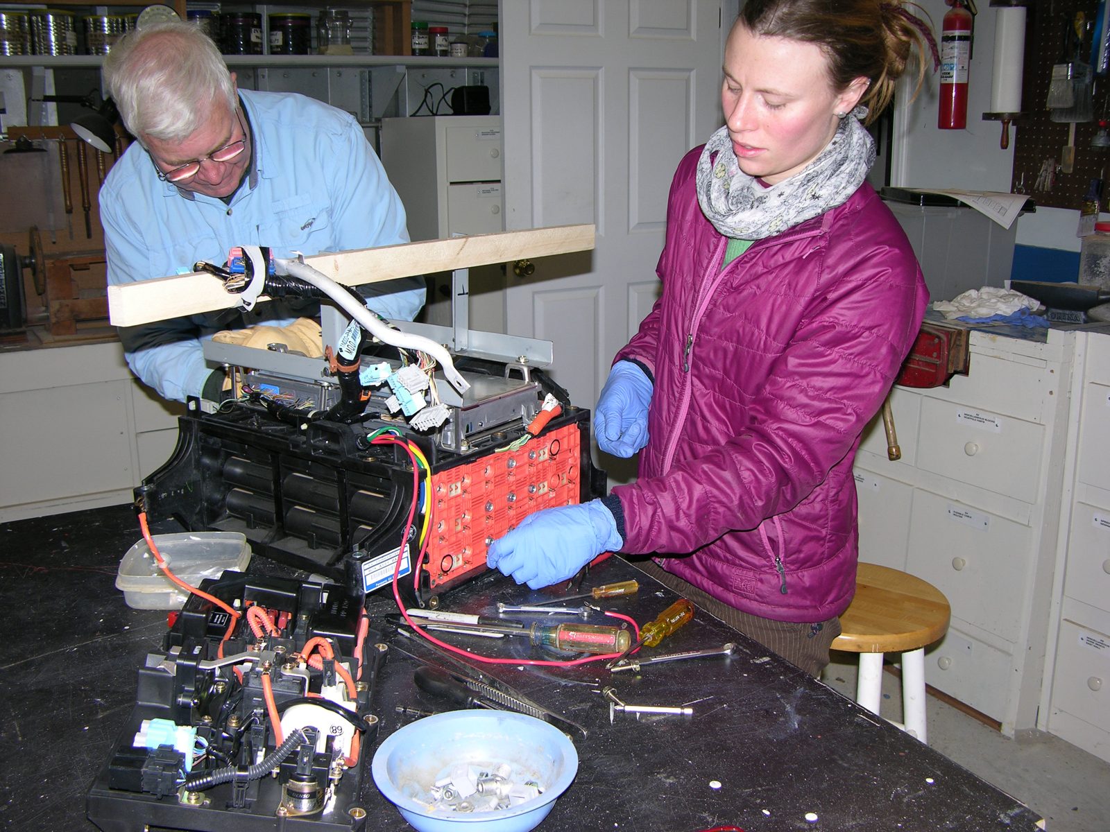 Working gloved on the exposed orange cell interconnect plate of the 144V pack